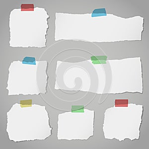 Pieces of torn white blank note paper with colorful sticky tape on gray background