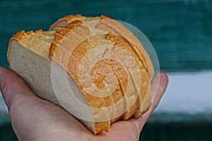 Pieces of white bread made from rifled loaf on the palm of the hand on a green background