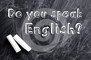 Pieces of white chalk and question DO YOU SPEAK ENGLISH written on blackboard