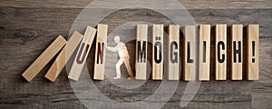 Pieces of wood with the german words for impossible and possible - mÃ¶glich unmÃ¶glich on wooden background