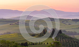 Pienza, Tuscany, Italy - January 24, 2024: Path to hill house through cypress trees and sunrise view of stunning rural landscape