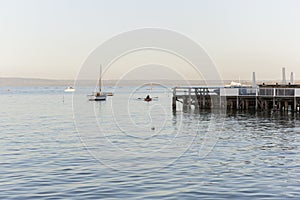 Pier Above The Ocean Surface And Lonely Man In Row Boat