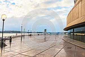 The pier at Bennelong Point in Circular Quay in Sydney Austraia - a woman runs beside the Opera House on a rainy morning