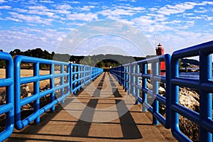 Pier with a bright blue fence in perspective. Big Red Lighthouse. Michigan, Ottawa County