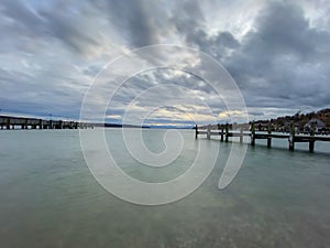 Pier with calm lake `Starnberger See` in Bavaria with smooth cloudy sky