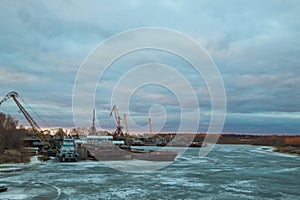 Pier with cargo ships on the frozen river.