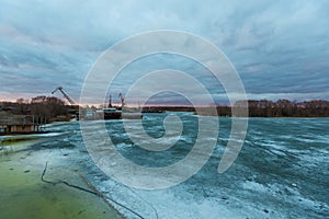 Pier with cargo ships on the frozen river.