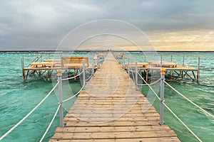 Pier with chaise longues in the sea in resort at sunset. Summer vacation. View at a clear sea with turquoise water. Summer vacatio