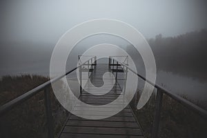 Pier on a foggy morning lake with mystical fog