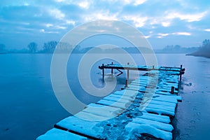 A pier on a frozen and misty lake