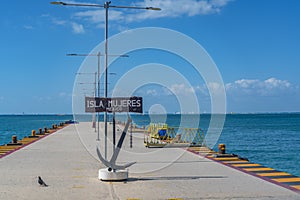 The pier from Isla Mujeres with the signe, background the sea and Cancun photo