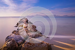 Pier/jetty of rock and stone, playa de muro, alcudia, mallorca, spain, sunrise over mountains, beautiful smooth sea