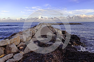 Pier / jetty of rocks covered in seaweed and beautiful sky, cala bona, mallorca, spain