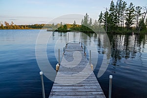 Pier jutting out into the Chippewa Flowage in front of a wooded island in the Northwoods