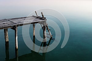 Pier with ladder with sunset colour reflections in the lake, El Remate, Peten, Guatemala