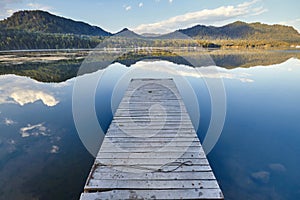 Pier on the lake on the background of sunset in a clear summer day. Warm summer evening on the dock. Fabulous views of the lake