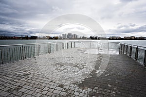 Pier of lake promenade with glass building multistorey residental house on background