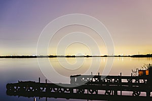 Pier on a lake at sunset with calm water and reflections of relaxing lights