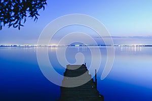 Pier on a lake at sunset with calm water and reflections of relaxing lights photo