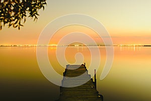 Pier on a lake at sunset with calm water and reflections of relaxing lights