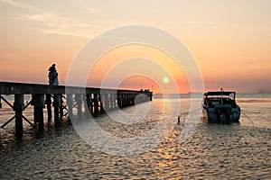 Pier landscape at sunset, people the going on a pier, happy people walking at the sea and observing a decline.