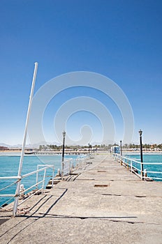 Pier leading to the sea on a sunny day/empty pier overlooking the sea on a sunny day