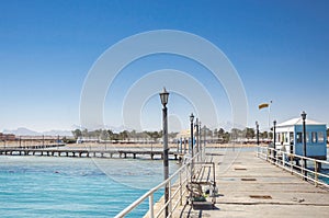 Pier leading to the sea on a sunny day/empty pier overlooking the sea on a sunny day