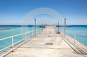 Pier leading to the sea on a sunny day/empty pier overlooking the sea on a sunny day