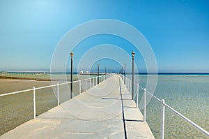 Pier leading to the sea on a sunny day/empty pier overlooking the sea on a sunny day