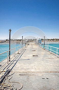 Pier leading to the sea on a sunny day/empty pier overlooking the sea on a sunny day