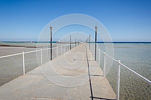 Pier leading to the sea on a sunny day/empty pier overlooking the sea on a sunny day