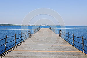 The pier near beach against blue sky in sunny day. Adriatic coast and sea in Slovenia. Holiday and travel concept