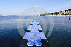 The pier near beach against blue sky in sunny day. Adriatic coast and sea in Slovenia. Holiday and travel concept