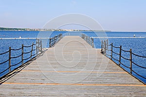 The pier near beach against blue sky in sunny day. Adriatic coast and sea in Slovenia. Holiday and travel concept