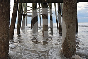 The pier pilings frame the ocean waves as they approach the shore