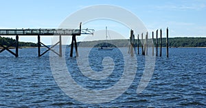 Pier with pilings and a sailboat in between