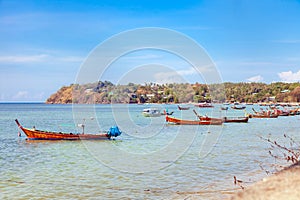 Pier Rawai beach in thailand on the island of phuket with old fishing wooden boats with long ropes moored to the shore