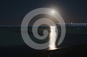 Pier on the sea illuminated by the moon.