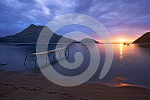 Pier and silend sea at the sunrise in the sandy beaches of Adrasan with a mountain view