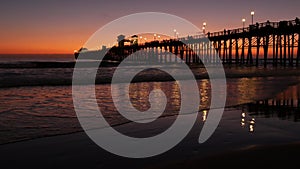 Pier silhouette Oceanside California USA. Ocean tide tropical beach. Summertime gloaming atmosphere.