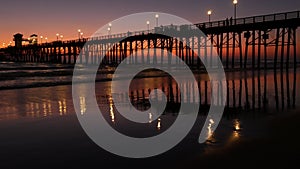 Pier silhouette Oceanside California USA. Ocean tide tropical beach. Summertime gloaming atmosphere.