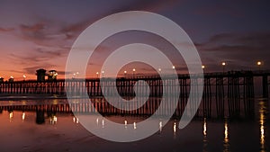 Pier silhouette Oceanside California USA. Ocean tide tropical beach. Summertime gloaming atmosphere.