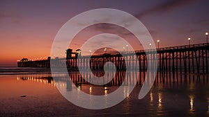 Pier silhouette Oceanside California USA. Ocean tide tropical beach. Summertime gloaming atmosphere.