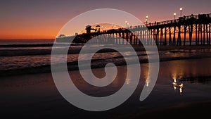 Pier silhouette Oceanside California USA. Ocean tide tropical beach. Summertime gloaming atmosphere.