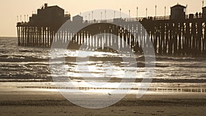 Pier silhouette at sunset, California USA, Oceanside. Ocean tropical beach. Seagull bird near wave