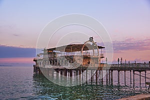 A pier stretching far out to sea against the sunset.