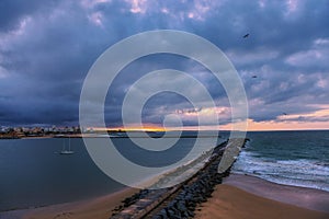 Pier to famous old farol de Portimao molhe este under gloomy sunset photo