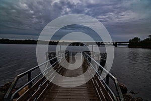 A pier towards the exmempt rail line with Dark storm clouds over the waves on Lake Wisconsin