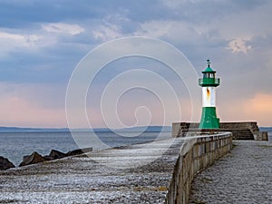 The pier in the town harbor of Sassnitz on the island of Rugen with the green and white lighthouse Ostmolenfeuer, Germany