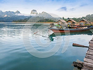 Pier with a traditional fishng boat on lake Cheow Lan, Thailand